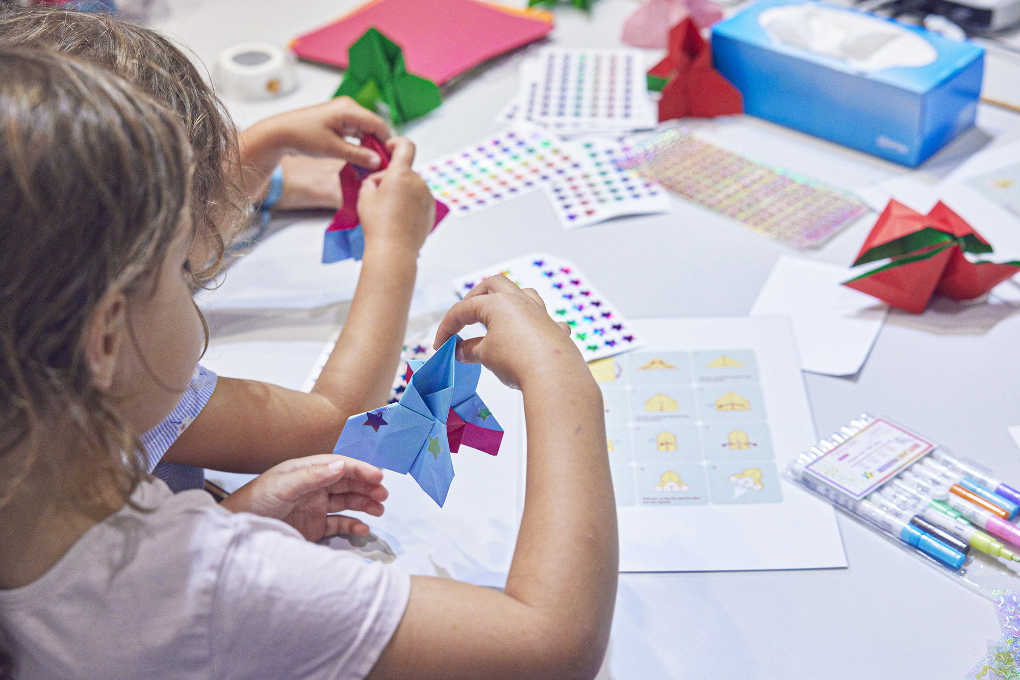 Children folding paper rockets at the stand of the Cosmology Group