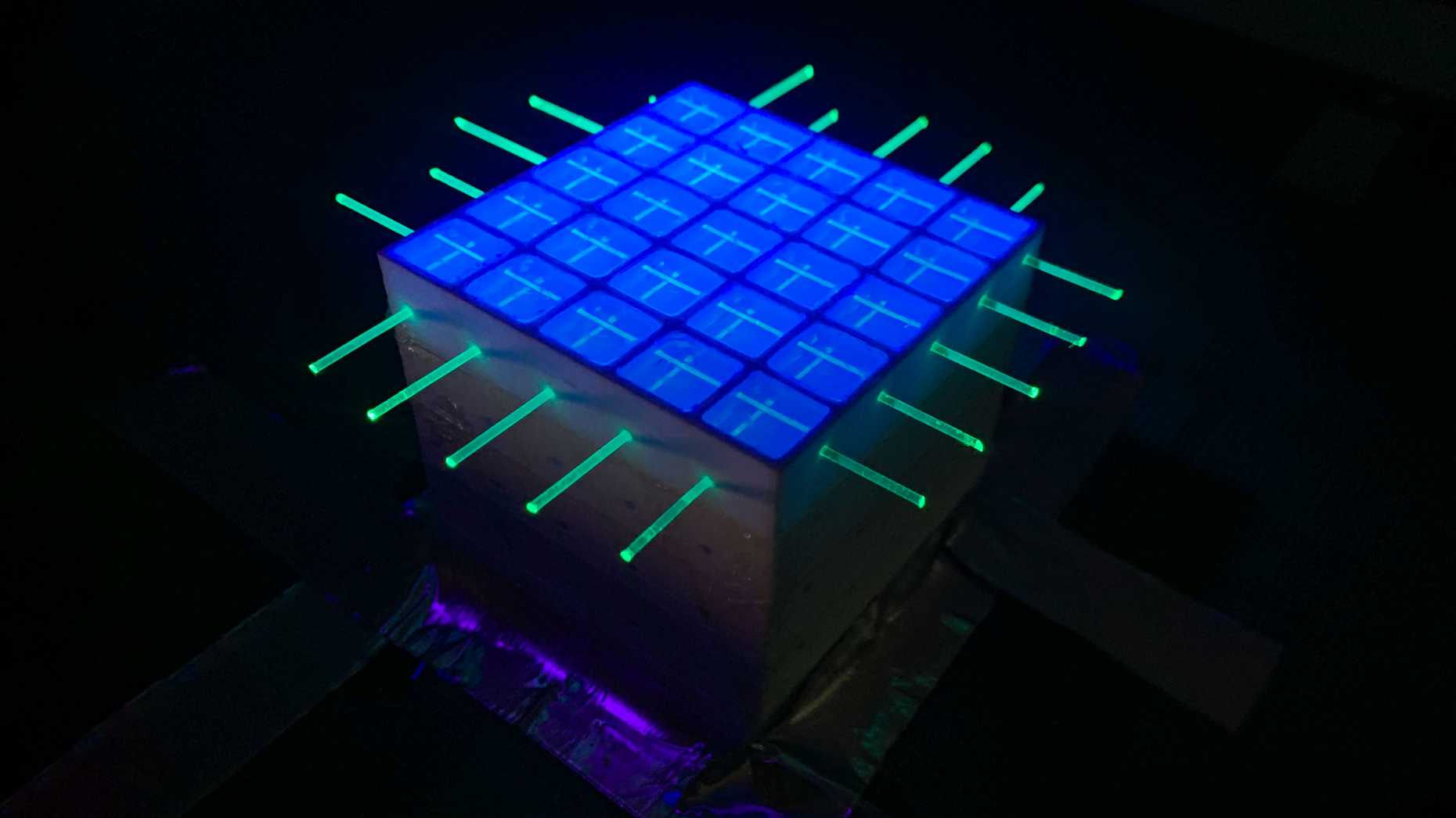 A SuperCube that's unsealed and illuminated with UV light to show the PS volume within each voxel and the fibres extending through the entire detector