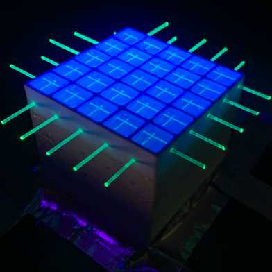 A SuperCube that's unsealed and illuminated with UV light to show the PS volume within each voxel and the fibres extending through the entire detector