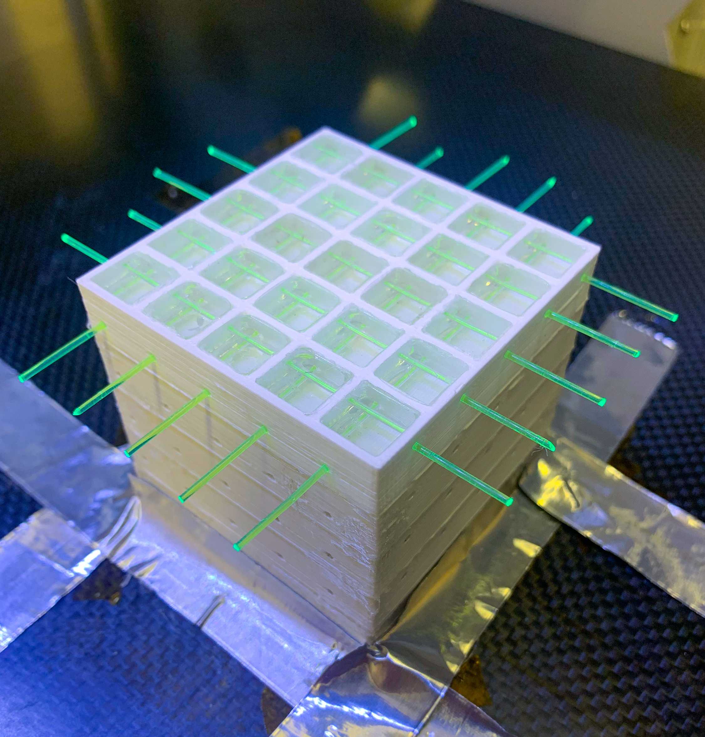 Photo of a manufactured SuperCube prototype with its top yet to be sealed to show the PS volumes within individual voxels and the optical fibers that pass through the detector